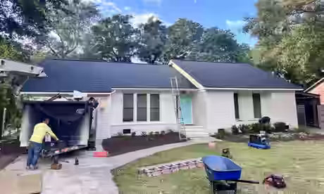 A finished new shingle roof on a white brick house